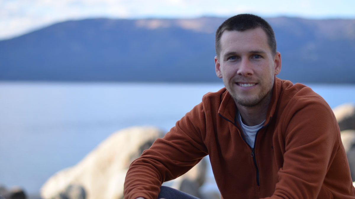 Zach Rodimel outdoors by a mountain lake